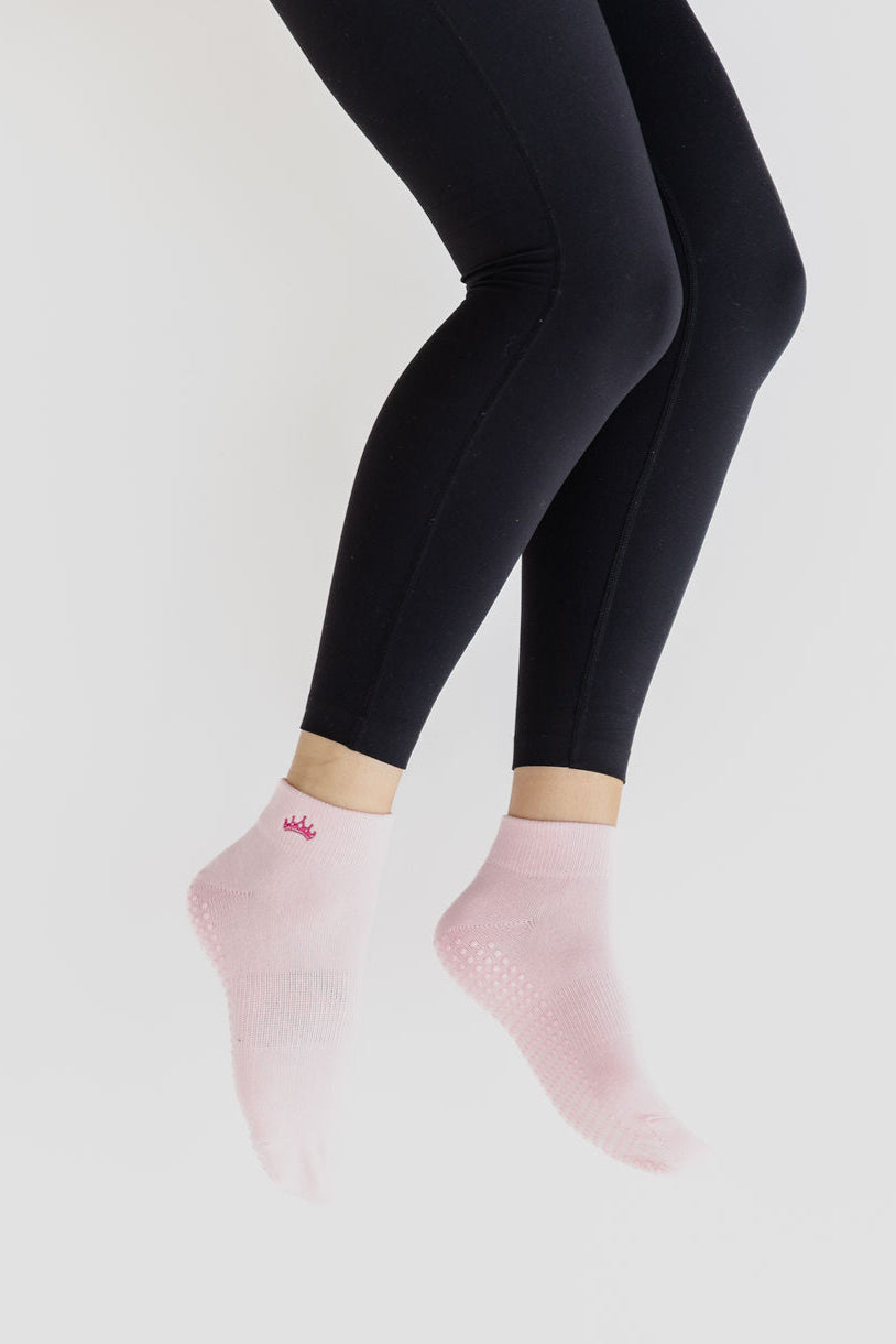 Person wearing black leggings and pink socks on a light gray background