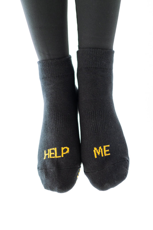 A pair of black ankle socks with 'HELP ME' text in orange on the side, suitable for workouts.